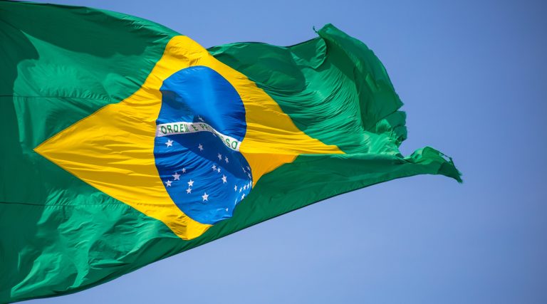 Flag of Brazil waving on blue sky background