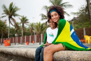 Young mother and son wrapped in Brazilian flag on Ipanema beach, Rio De Janeiro, Brazil